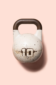 White Kettlebell on a pink background for strength training and fitness