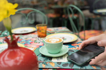 close-up cup of coffee female hands holding phone
