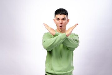 An Asian man in a green sweatshirt stands against a white background, crossing his arms in an 
