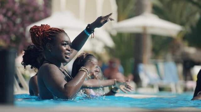 Group of happy smiling dancing black women enjoying a sunny poolside celebration dancing in slow motion