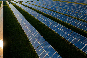 Drone view of blue solar panels on agricultural field during sunny day. The landscape is fully...