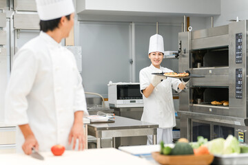 厨房・キッチンで働く料理人・調理師の男女
