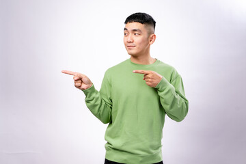 An excited Asian man in a green sweatshirt points in both directions with a wide smile and an...