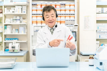 病院・薬局でパソコンを使ってオンライン服薬指導・診療する薬剤師・調剤師の男性（処方箋・医師） 