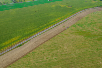 Top view of a tractor plowing the land near the railway and a corn field. Season of work on the...