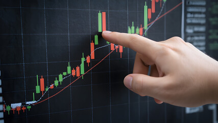 A close-up of hands pointing at stock market candlestick charts, illustrating market trends, price movements, and financial trading analysis.