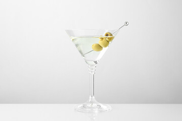 Martini cocktail with olives in glass on light table