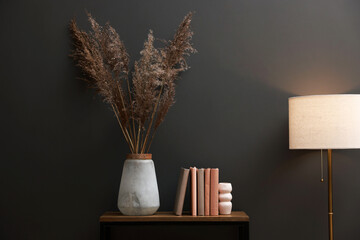 Console table with decor and lamp near grey wall in room. Interior design