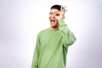 A cheerful Asian man in a green sweatshirt makes an 
