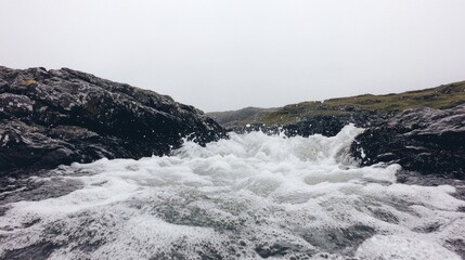 Coastal waves crashing between rocks on a foggy day