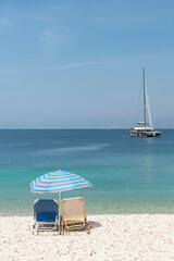 Boat on the sea with beach umbrella and chairs on the shore