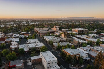 High-angle view of downtown Bend at dawn. Buildings and streets are visible, with trees and parking lots. Downtown, Bend, Oregon, United States