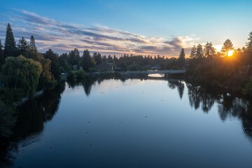 Sunrise over a tranquil Mirror Pond lake, with a bridge and houses in the background. Peaceful...