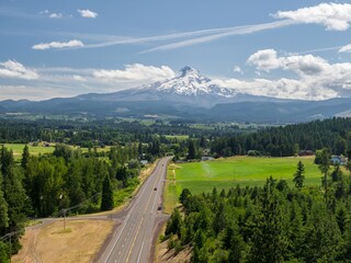 Empty two-lane highway winds through rural Oregon countryside, Mount Hood in the background. Irrigation system watering a field. Oregon, United States