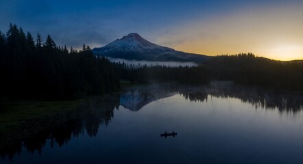 Misty morning on Trillium Lake, two kayakers paddle near Mount Hood. Peaceful, tranquil scene.  Oregon, United States