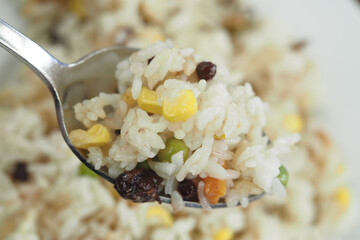 Colorful rice dish garnished with peas, corn, and raisins