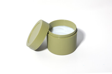 A minimalist beauty product shot featuring an open olive-green cosmetic jar filled with white cream. Captured against a clean white background, this high-quality image is perfect for skincare