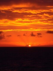 Naklejka premium A vibrant sunset over the sea with intense golden and amber hues filling the sky, casting reflections on the water