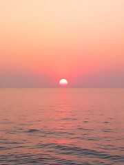 Obraz premium A peaceful sunset over the sea with a soft gradient of gold, pink, and lavender in the sky, reflecting on calm waters