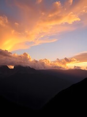Obraz premium Sunset Over Mountains with Dramatic Clouds Lit by Golden Light