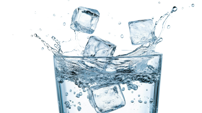 A glass of water with ice cubes splashing