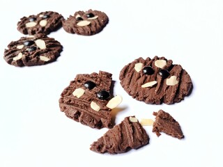Broken chocolate cookies with chocochip topping and almond slices isolated on white background.