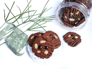 A jar of chocolate cookies and artificial flowers on a white background. Eid al-Fitr celebration
