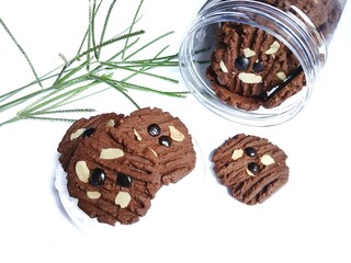 A jar of chocolate cookies and artificial flowers on a white background. Eid al-Fitr celebration
