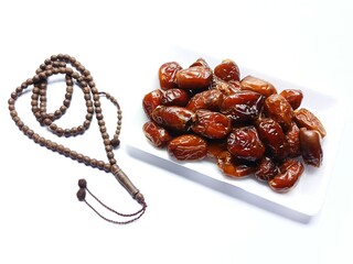 Sweet and delicious dates on gingham and prayer beads isolated on white background.