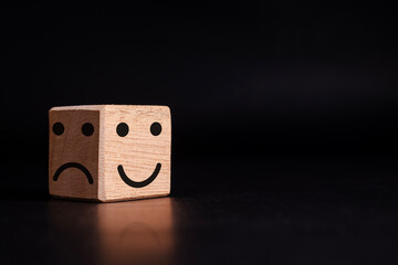 smile expression emoji on bright side and bad expression on dark side on wooden cube on isolated o...