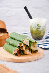 Serabi Solo on wooden plate. Traditional pancakes from Solo, Central Java. Made from flour dough baked on a special clay plate. Filled with various toppings then wrapped with banana leaf rolls	