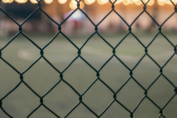 Fototapeta premium Chain Link Fence with Blurred Sports Field Background