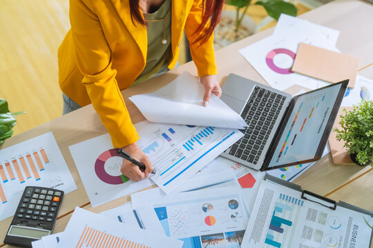 businesswoman hand closeup Deciphering some business data graph charts and laptop for marketing analyzing and business strategic planning in co-working office Analyzing business charts