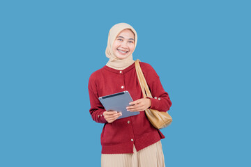 A woman wearing a red sweater and a tan skirt is holding a tablet in her hand. She is smiling and she is excited about something