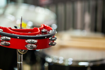 A close-up of an orchestral tambourine fragment against a blurred background of percussion instruments