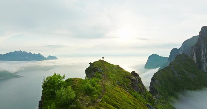 Hiker on majestic arctic Senja mountain ridge with spectacular view; drone