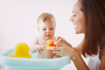 Mother, child and baby in bathtub with rubber duck for cleaning, hygiene and wellness for health in home. Kid, parent and infant wash with toy in bathroom for skincare, playing and morning routine
