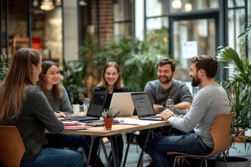 Marketing team discussing new project during meeting with laptops in modern office