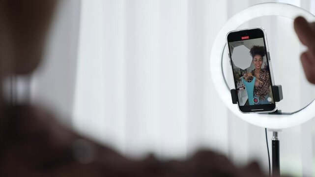 Rear view behide woman influencer shoot live stream vlog video review clothe crucial social media or blog. Girl with apparel studio lighting for marketing recording session broadcasting online