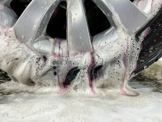 Car wheel cleaning process. Rim cleaner gives purple chemical reaction when removing metal or iron...