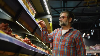 Senior man shopping for lettuce and cabbage in grocery store - Powered by Adobe