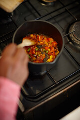 Hands, cooking and person with soup, stirring and ingredients for food in small business, closeup or catering. Startup, entrepreneur and vegetables for stew in kitchen, chef and meal prep for cuisine