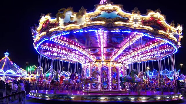 Vibrant video of a spinning carousel at night, captured from a low angle. The bright lights create a lively, festive atmosphere.
