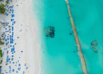A beach with many people and chairs, and a blue ocean