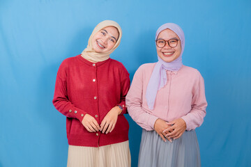 Two women wearing glasses and scarves are posing for a picture. They are both smiling and making...