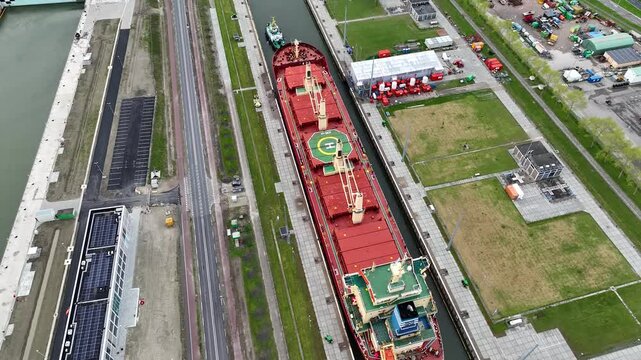 Aerial drone view of a ship passing through a canal sea lock in the Netherlands. Inland shipping sluice where lots of ships pass through.
