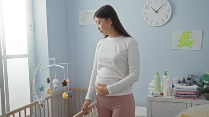 Woman standing in a cozy nursery with a crib, surrounded by baby items and soft toys, gently cradling her stomach, showcasing a peaceful moment in a sunlit room.