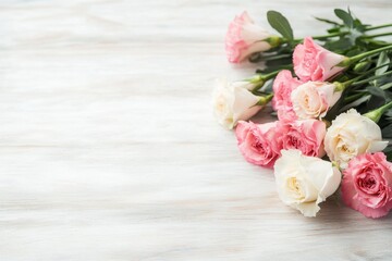 A soft pastel bouquet of pink carnations and cream-colored roses, resting on a rustic wooden table