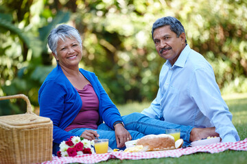 Portrait, smile and picnic with old couple in nature for flowers, happiness and anniversary date. Health, peace and bonding with senior man and woman in park for food, relax or retirement together