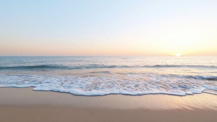 Obraz premium Serene ocean shore at sunrise with gentle waves and soft sunlight on the horizon, creating a peaceful ambiance.